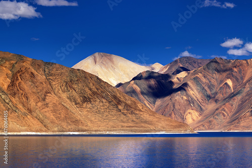 Reflection of Mountains on Pangong tso (Lake) with blue sky in background. It is huge lake in Ladakh, It is 134 km long and extends from India to Tibet. Leh, Ladakh, Jammu and Kashmir, India