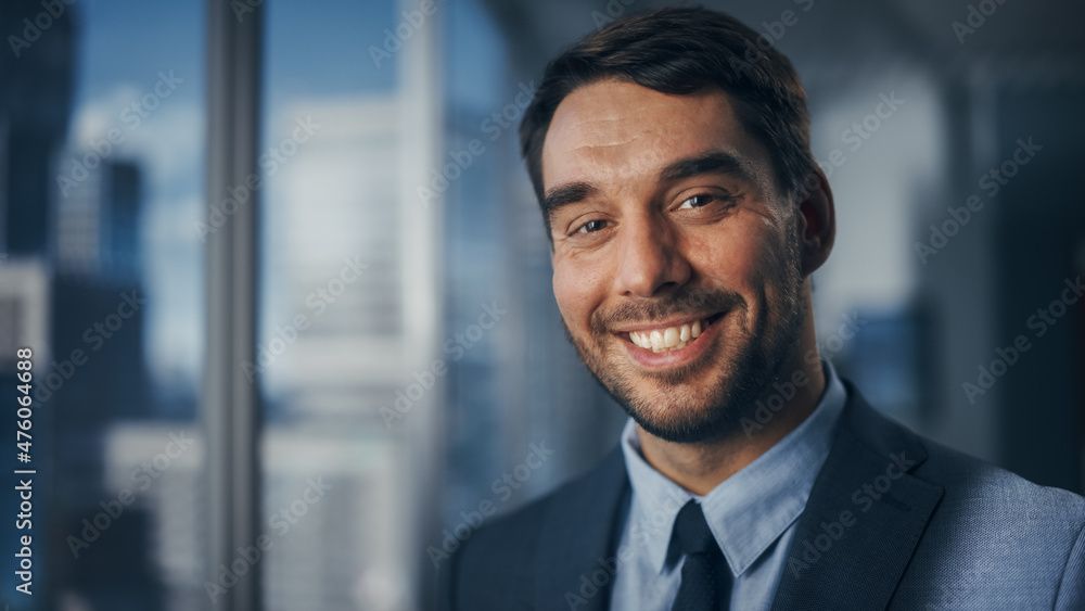 Close Up Portrait of Handsome Caucasian Businessman in Stylish Black Suit Posing Next to Window in Big City Office with Skyscrapers. Confident Male CEO Smiling. Successful Masculine Business Manager. Close Up Portrait of Handsome Caucasian Businessman in Stylish Black Suit Posing Next to Window in Big City Office with Skyscrapers. Confident Male CEO Smiling. Successful Masculine Business Manager.