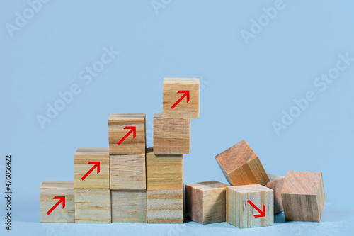 Collapsed stair structure of wooden cubes with upward pointing arrows, business risk due to inflation, global crisis or unsustainable financial concept, light blue background with copy space photo