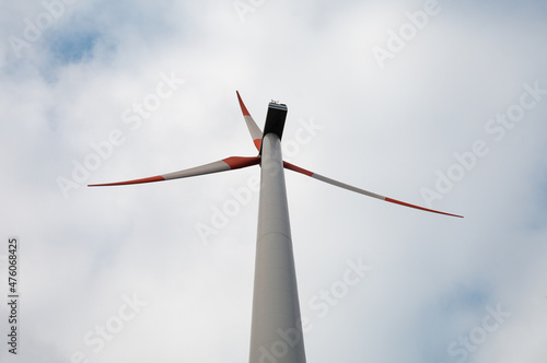 Detail of wind turbine against blue sky. Renewable energy - ecological concept. Close up photo of windmill with cloudy blue sky.