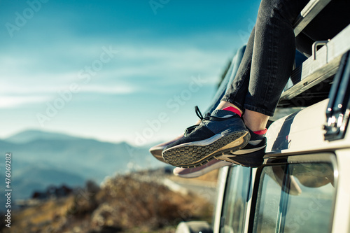Persons enjoying view from roof rack of off-road vehicle