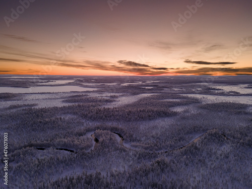 Snowy landscape of Ylläs. Petäjäjoki in the middle of the forest. Daylight or sunset during the polar night time in Lapland, Finland