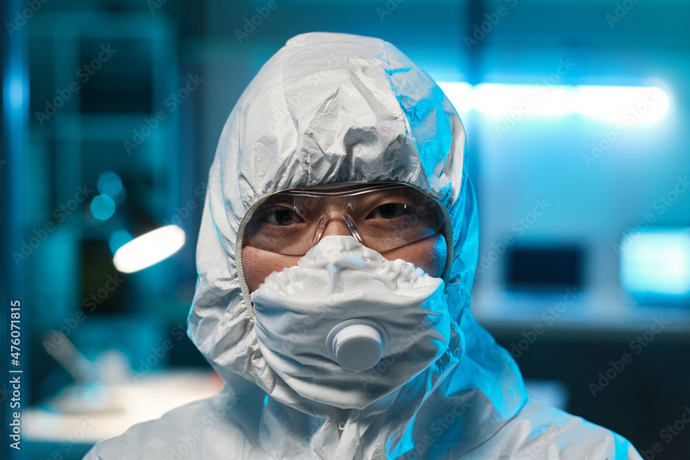 Head of young Asian female laboratory worker or scientist in protective eyeglasses, respirator and coveralls Head of young Asian female laboratory worker or scientist in protective eyeglasses, respirator and coveralls