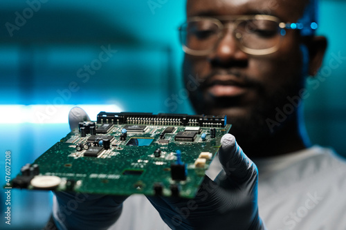 Obraz na płótnie Circuit board in gloved hands of young contemporary African laboratory worker ho