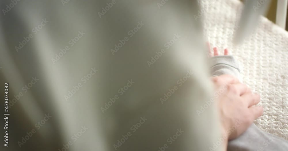 Close up of a crying newborn baby lying on its back in a child crib. Mom calms neonate toddler at home in kids bedroom. Authentic footage. The concept of childhood, New life, Fatherhood. Close up of a crying newborn baby lying on its back in a child crib. Mom calms neonate toddler at home in kids bedroom. Authentic footage. The concept of childhood, New life, Fatherhood.
