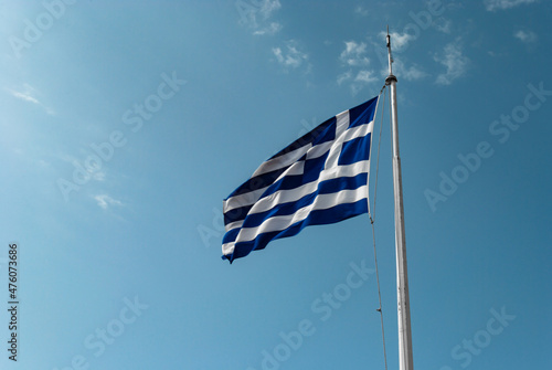 The Greek flag flies against the blue sky