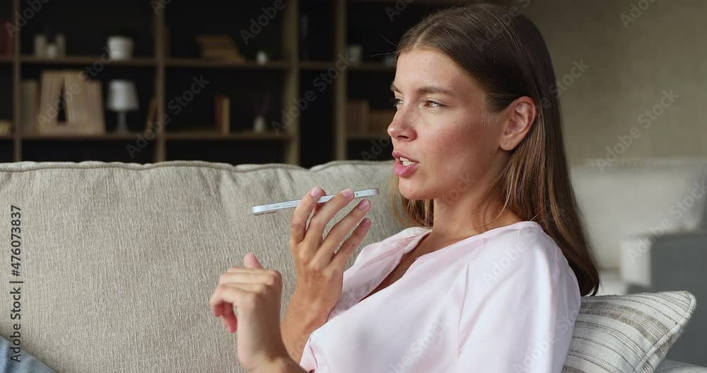 Young attractive woman sit on sofa at home, makes call talks on speakerphone, younger gen and comfort usage of modern tech. Send voice message, voice mailing, share news. Remote communication concept Young attractive woman sit on sofa at home, makes call talks on speakerphone, younger gen and comfort usage of modern tech. Send voice message, voice mailing, share news. Remote communication concept