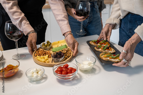 Close-up of mature women serving appetizers and sandwiches on the table preparing for dinner party