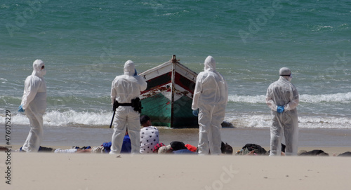 Illegal migrants at the coast of Cadiz, Spain, guarded by the police in protective suits. photo
