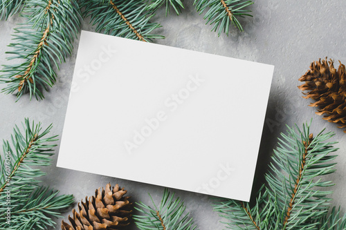 Christmas greeting card mockup with fir tree branches and cones on grey background