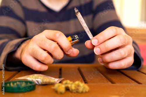 Front view of young person smoking cannabis joint on a table full of weed.