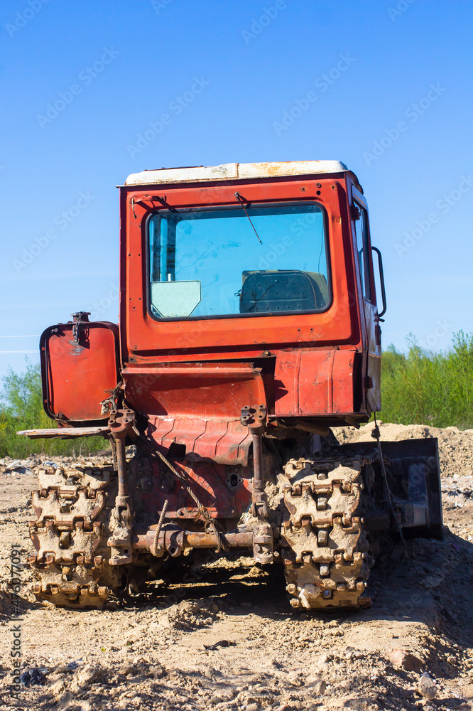 Fototapeta premium Old red bulldozer against the blue sky. Back view.
