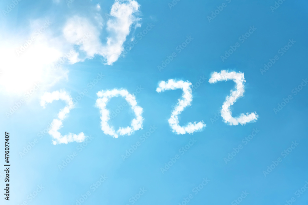 Numbers 2022 symbol inscription on a background of blue sky from white smoke of clouds lit by a bright sun. Numbers 2022 symbol inscription on a background of blue sky from white smoke of clouds lit by a bright sun.