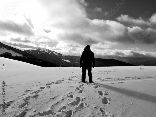 black and white photo of man from behind looking at the horizon on the snowy mountain