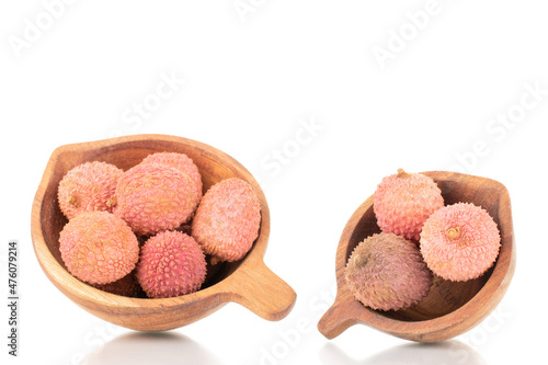 Several ripe organic litchi fruit with wooden utensils, close-up, isolated on white.