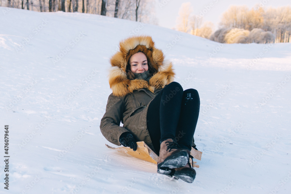 Young woman sliding downhill on piece of paperboard in park. Young woman sliding downhill on piece of paperboard in park.
