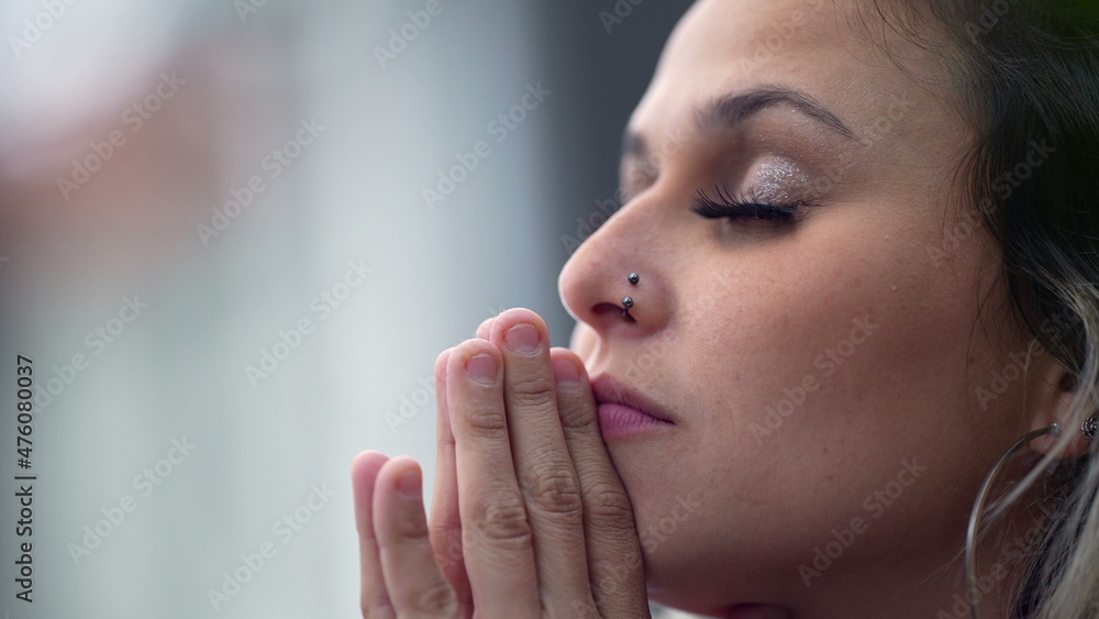 Young woman closing eyes in meditation and contemplation, person praying - obrazy, fototapety, plakaty 