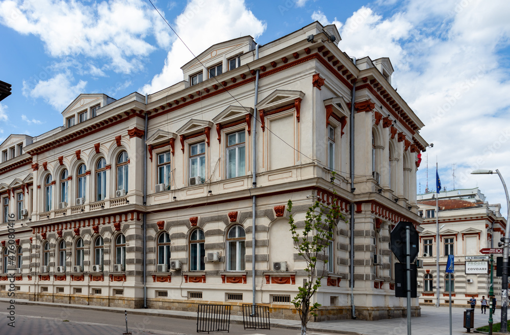 Obraz premium Bacău, Romania-May 2, 2021: Impressive building, historical monument, Administrative Palace in Bacău, Moldova, side view showing the architecture of the windows on a background of blue sky