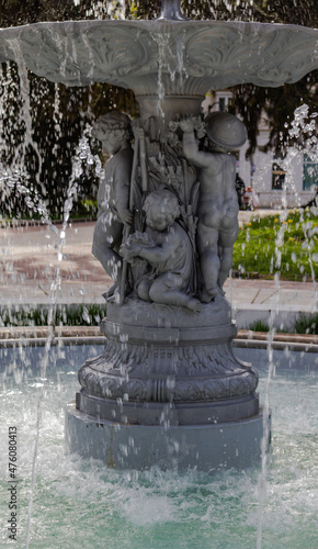 The texture of water flowing in an artesian well  which shows a gray sculpture of small children