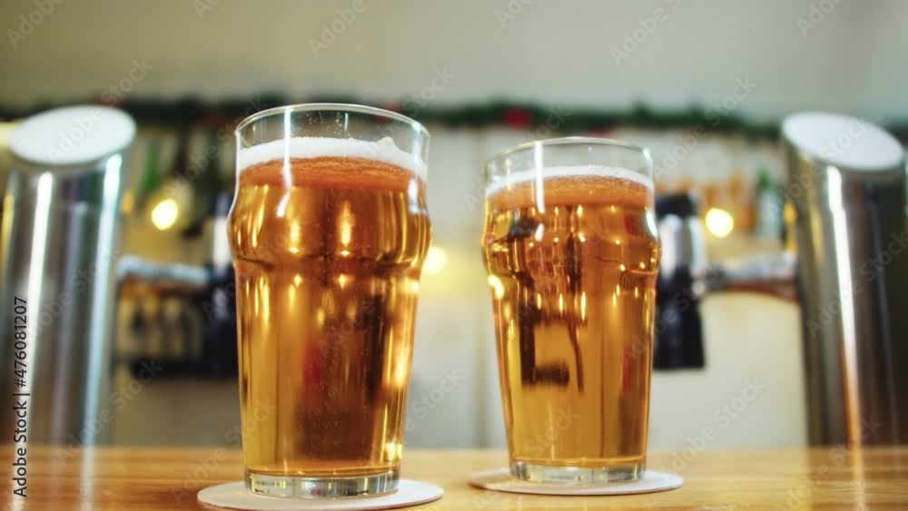 Foamy beer in glasses close-up. Alckohol golden beer drink in mugs. Macro shooting of fresh pale ale on bar counter background in pub. Foamy beer in glasses close-up. Alckohol golden beer drink in mugs. Macro shooting of fresh pale ale on bar counter background in pub.