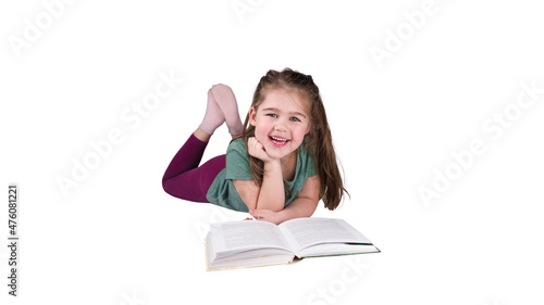 isolated girl lies on her stomach and smiles in front of an open book on a white background