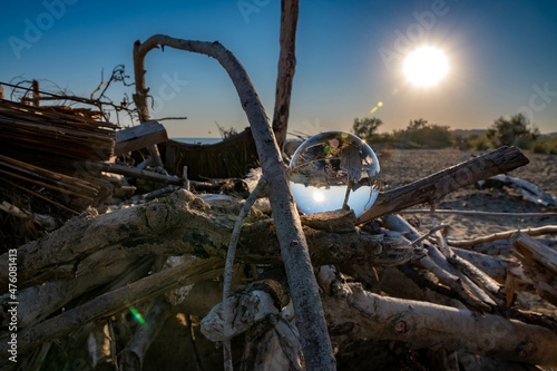 Glass ball on woods in the beach of Bibione, Italy against a sunny blue sky photo