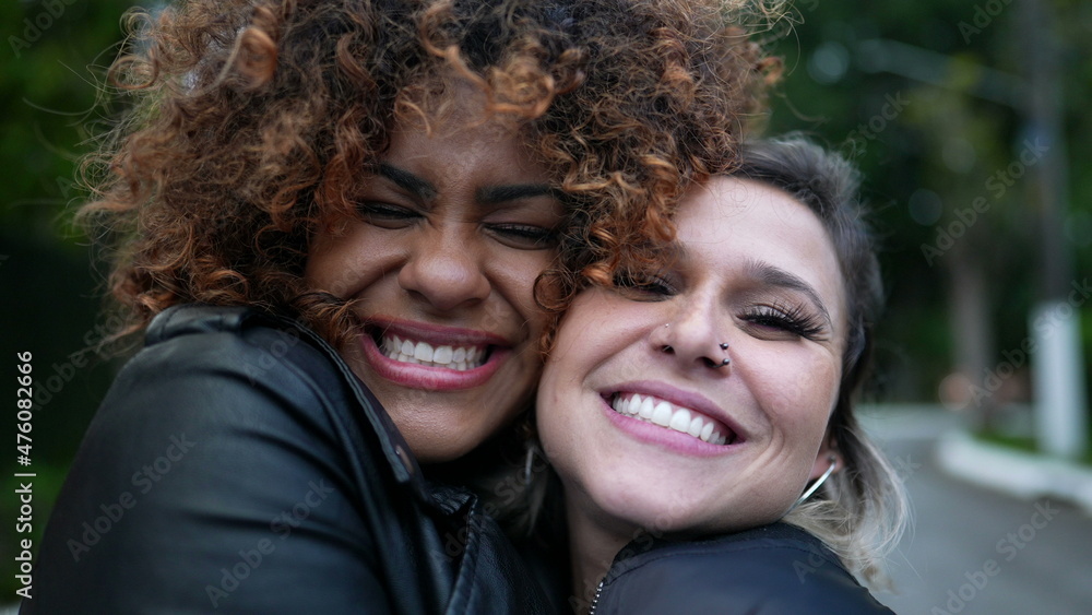 Diverse friendship, two young women embrace cheek to cheek, diversity concept