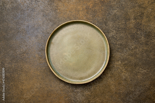 Top view empty green ceramic plate on brown rustic background, copy space