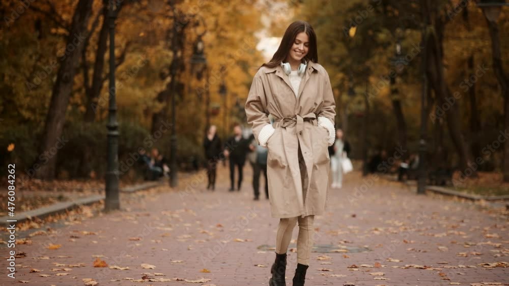 Attractive stylish woman walking in park dressed in coat autumn trendy street fashion style accessories. Beautiful girl in autumn outdoor