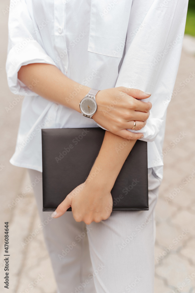 girl holding a book white shirt, black book wrist watch