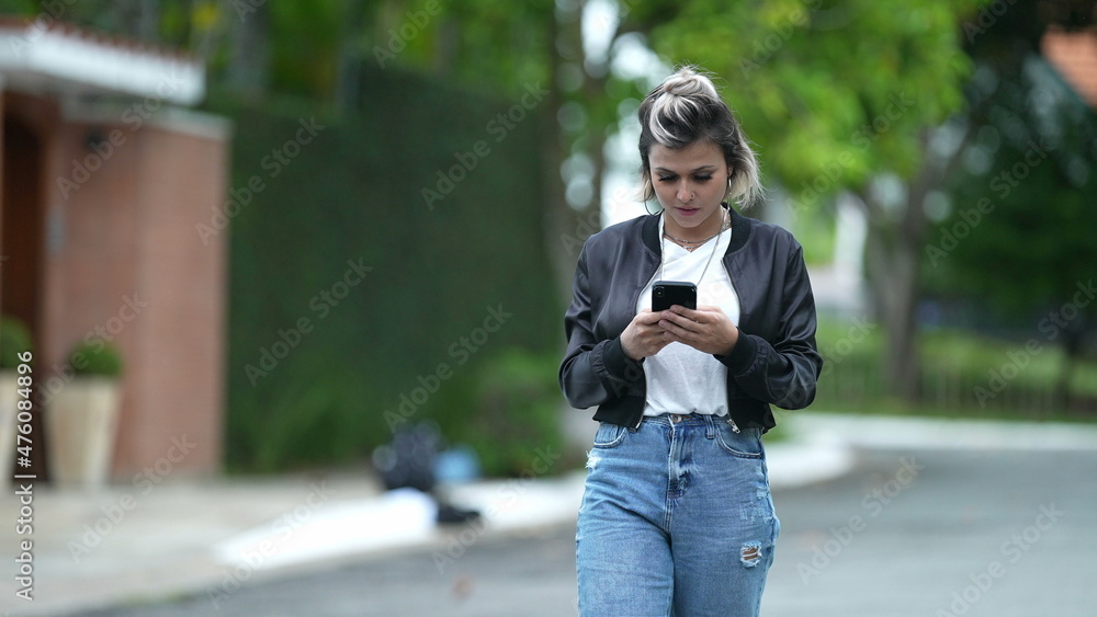 Happy woman staring at phone screen while walking outside