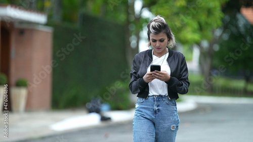 Happy woman staring at phone screen while walking outside