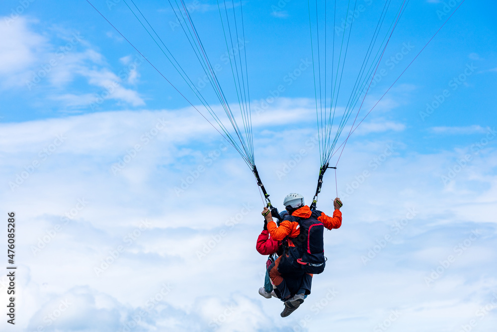paragliding against the backdrop of cumulus clouds and blue sky paragliding against the backdrop of cumulus clouds and blue sky