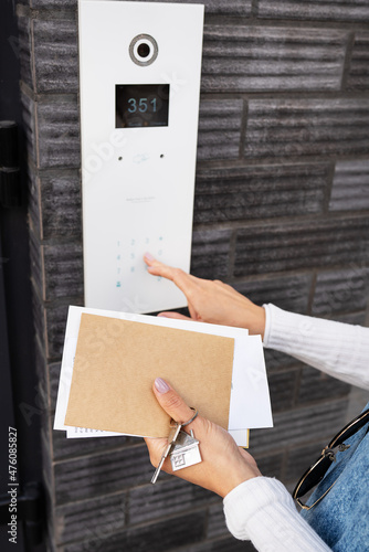 Door Access Control - A young woman, holding her mail in her hands, enters the code to open the door. Code door. photo