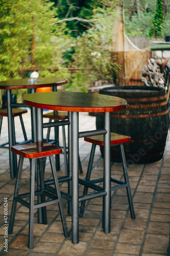 High metal table with wooden top and low stools in a street cafe