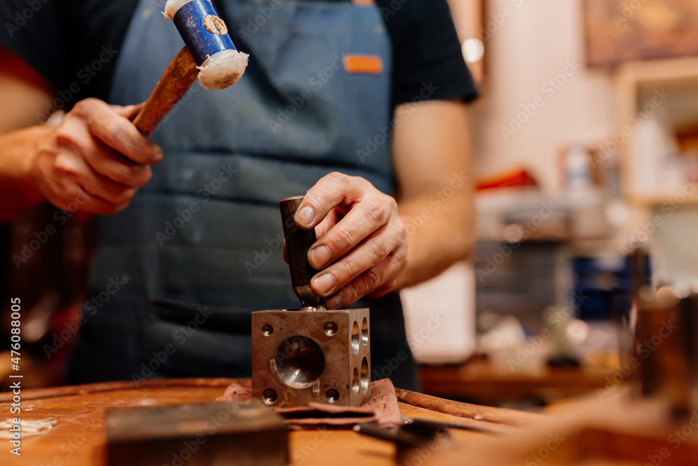 jeweler using his tools to shape a ring. worker using a rubber hammer. jeweler using his tools to shape a ring. worker using a rubber hammer.