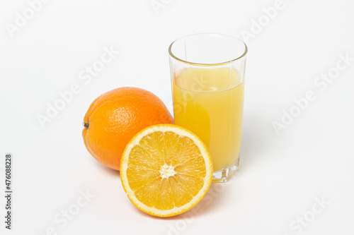 Freshly squeezed orange juice on a white background. A glass of orange juice and a cut orange next to it. Refreshing natural fruit juice