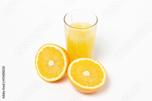 Freshly squeezed orange juice on a white background. A glass of orange juice and a cut orange next to it. Refreshing natural fruit juice