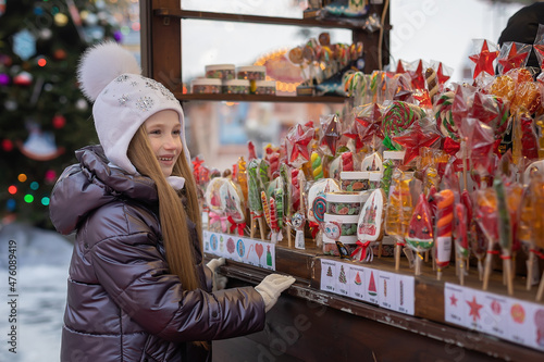 girl looks, chooses, buys caramel, lollipops, candies at the Christmas market © Анна Перфилова