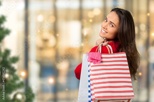 A beautiful happy girl holds shopping bags in hands and smiles after Christmas shopping in the mall.