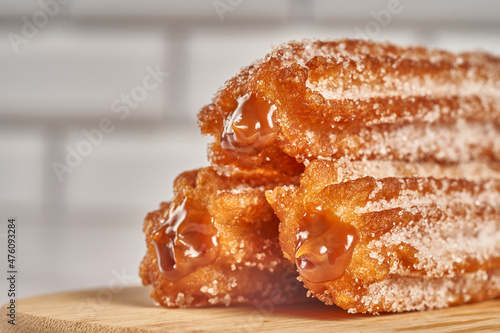three churros filled with dulce de leche caramel on a wooden board photo