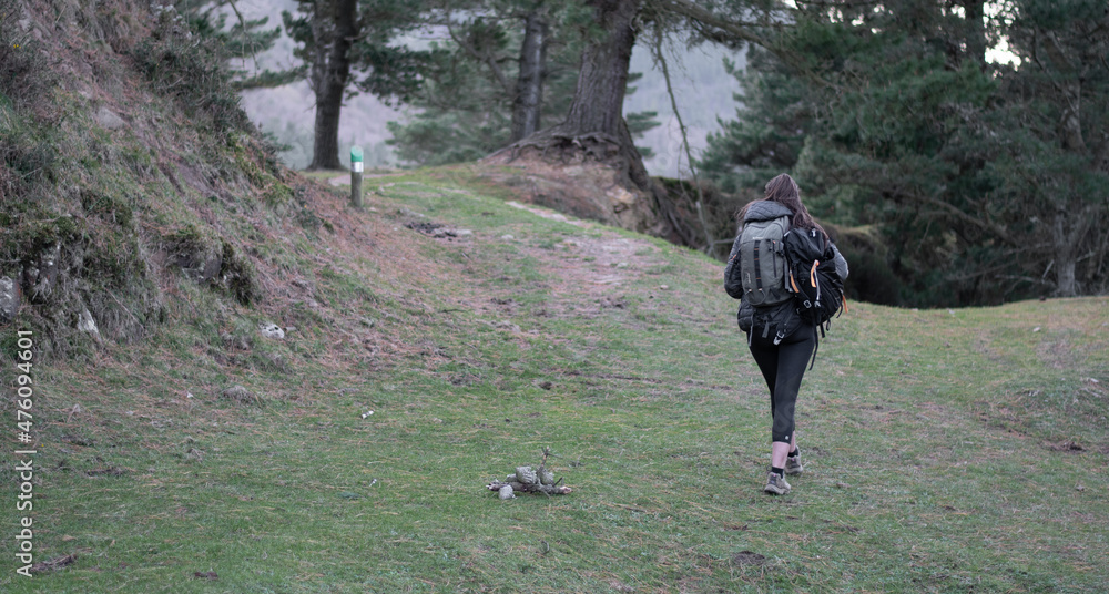 chica con mochilas caminando por el bosque