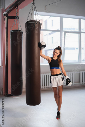 Female athlete boxing the punching bag in urban industrial gym