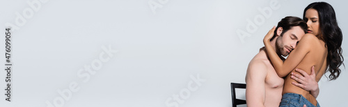 sexy woman hugging man sitting on chair with closed eyes isolated on grey, banner.