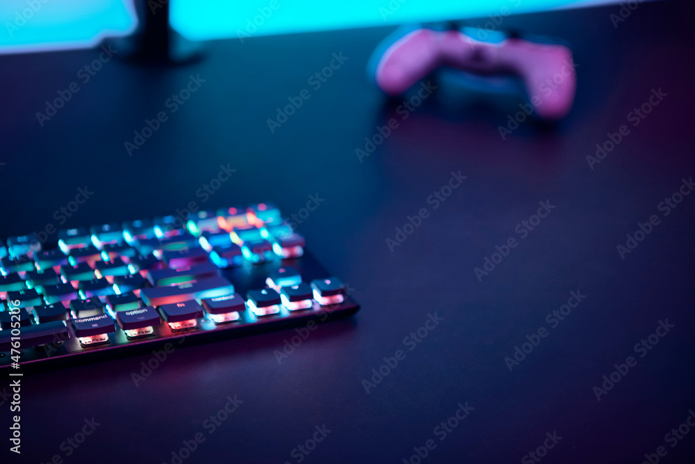Fototapeta premium Gaming keyboard with color backlit and game controller on dark table.