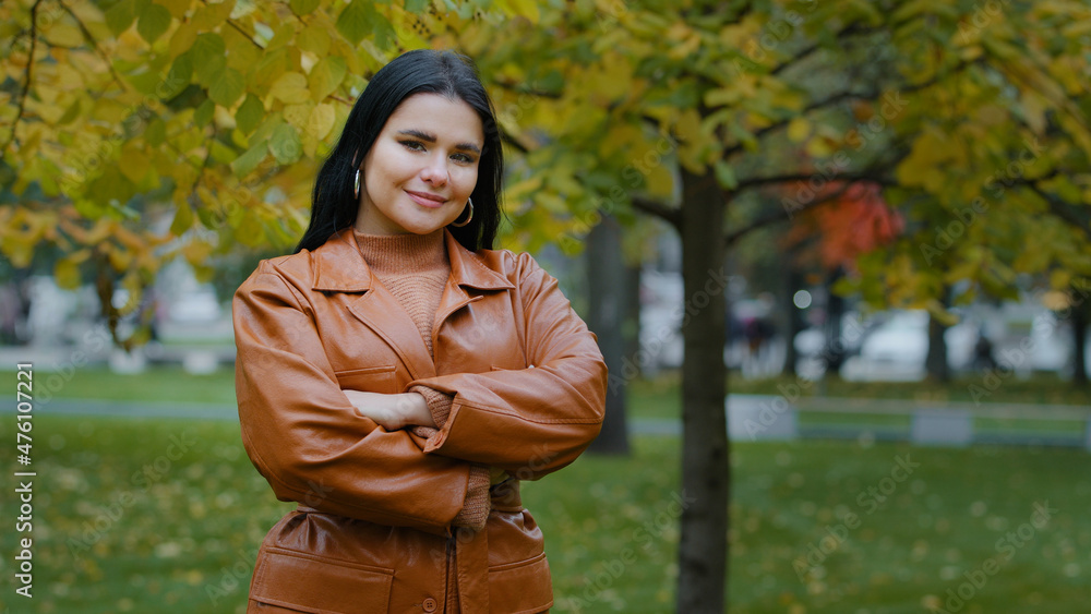 Beautiful young elegant woman looking at camera focuses gaze crossed arms over chest smiles shyly posing attractive pretty Hispanic girl stand in city autumn park outdoors portrait happy female Beautiful young elegant woman looking at camera focuses gaze crossed arms over chest smiles shyly posing attractive pretty Hispanic girl stand in city autumn park outdoors portrait happy female