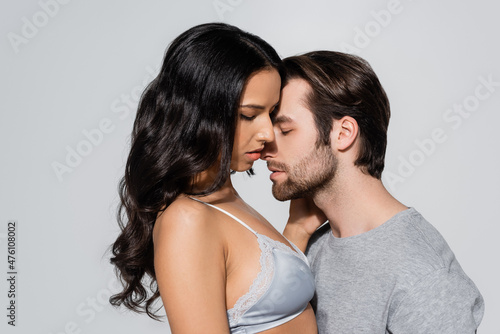 man with closed eyes near sexy woman in satin bra isolated on grey.