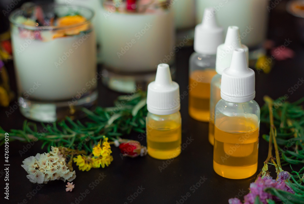 Aroma oil bottles top view on black table. Ingredients for homemade candle making. Essential oil bottles. Dried flowers decor. Aroma oil bottles top view on black table. Ingredients for homemade candle making. Essential oil bottles. Dried flowers decor.