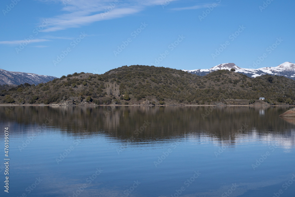 The lake in a sunny morning. Panorama view of the forest, mountain, cliffs, lake and the perfect reflection of the sky and woods in the blue water surface.
