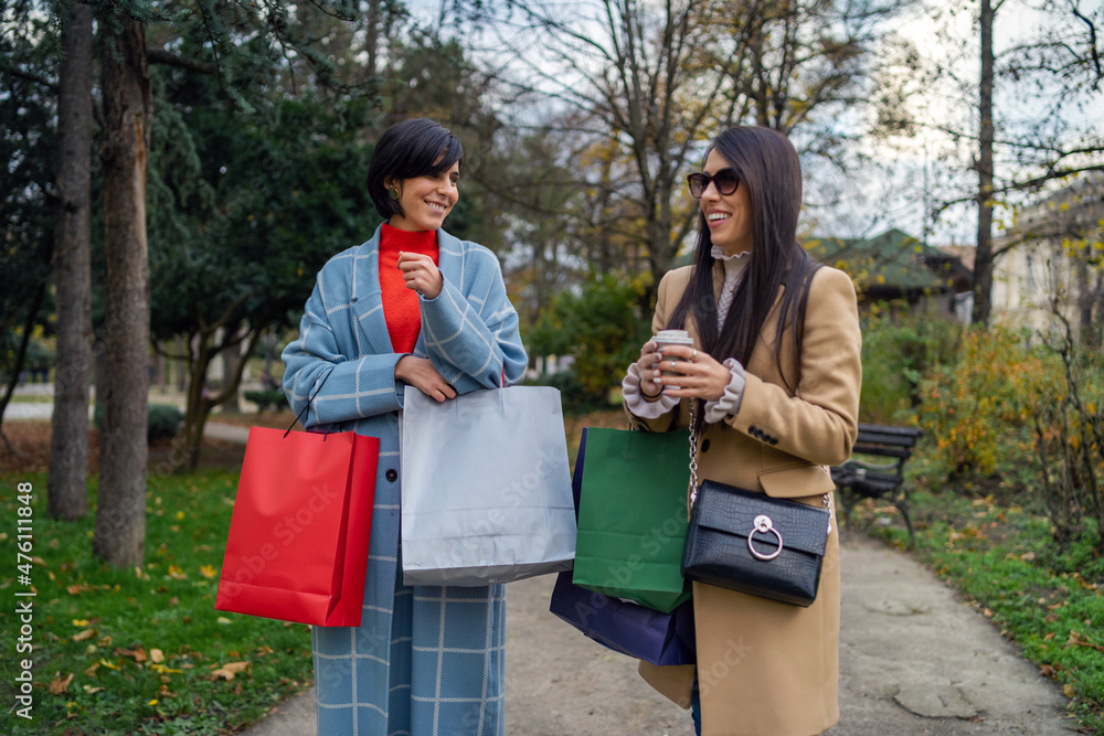 Two beautiful young women with shopping bags walking down the street
